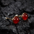 Macro shot of red round gemstone earrings in gold setting on black charcoal background - Natural Red Agate Round Gold 5mm