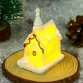 Close-up of a white resin Christmas church miniature with LED lights and snow texture - Style B