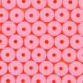 Perline rotonde in pasta polimerica rosa per gioielli fai-da-te con foro su sfondo arancio - rosa acceso
