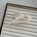 Vue détaillée d'une pince à cheveux torsadée beige translucide sur un présentoir neutre - Blanc Gelée