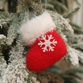 Plush red Christmas stocking ornament with white snowflake hanging on a snowy pine branch - Snowflake