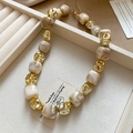 Detail of beaded necklace with beige marble beads and gold plated accents in a jewelry box - Beige Necklace