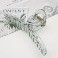 Detail of large translucent sage green hair claw clip with golden spring on marble - Dark Green