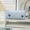 Light blue quilted pencil case with bow embroidery and zipper on a white desk - Blue