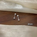 Detail eines 3mm Zirkonia-Ohrsteckers mit Schraubverschluss auf strukturiertem Holzhintergrund - Kleiner Stil / Silber Einzelner Zirkon