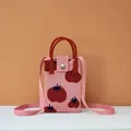 Detail of pink knitted mobile phone bag with red tomato patterns and round handle - Persimmon Good Fortune (Pink)