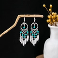 Detail of bohemian silver dreamcatcher earrings with turquoise beads and feather tassels - Blue