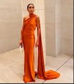 Detail eines orangefarbenen Satin-Abendkleids mit langem Schulterumhang und elegantem Fall - Orangerot