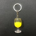 Macro detail of wine glass keychain with liquid yellow resin on black leather base - Yellow