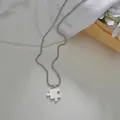 Vista detallada del collar con colgante de rompecabezas plateado sobre un fondo de regalo - Estilo de Mujer