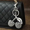 Silver cherry keychain with sparkling rhinestones attached to a black quilted handbag - Rhinestone Cherry Silver Leaf White