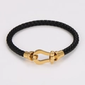 Dettaglio di un bracciale in pelle intrecciata nera con chiusura a ferro di cavallo - Oro (Corda Nera)