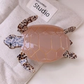 Detail of a turtle-shaped acetate hair claw with pink glossy finish and shell pattern - Large / Brown