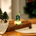 Detail showing the warm LED glowing belly of a knitted Christmas gnome decoration - Green Short Leg Style