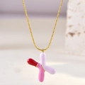 Detail of gold star necklace featuring pink and white enamel inlay on a delicate chain - Letter X
