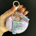 Détail du porte-clés lettre F en résine avec pompon violet et paillettes en cœur - Lettre F