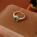 Dettaglio dell'anello con zircone ovale verde scintillante su una scatola di velluto marrone - Aperto Regolabile / Argento-Verde