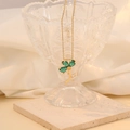 Detail of green clover pendant necklace hanging on glass with cubic zirconia accents - Peacock Green