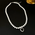 Detail view of a white faux pearl necklace featuring a black heart-shaped pendant on black backdrop - Black Heart Pearl
