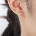 Elegantes pendientes de corazón plateados con circonita usados por una modelo femenina - Stud aretes / Color Acero