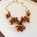 Détail du collier léopard vintage avec pétales ambrés et perles rouges centrales - Brun doré