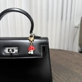 Détail d'un porte-clés champignon en émail rouge avec perle sur un sac à main en cuir noir - Champignon Perle Fraise