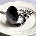 Vintage Alice in Wonderland style black metal pocket watch on white embossed ceramic plate - Gunmetal