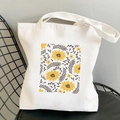 Cream canvas tote bag with yellow cosmos flower print resting on a black chair - Yellow Rectangle Floral