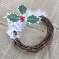 Gros plan de couronne de rotin de Noël avec feuilles vertes et baies rouges d'hiver - Couronne de Vigne en Herbe Blanche 15cm