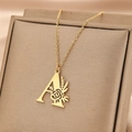 Detail einer goldenen Kette mit Buchstabe A und Rosenanhänger auf braunem Samt-Schmuckkästchen - Buchstabe A