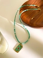Macro detail of bohemian beaded necklace with green bird pendant on a wooden tray - Green Square Plate