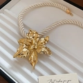 Dettaglio di un ciondolo floreale dorato con collana a corda intrecciata bianca - Collana con fiori 3D oro (corda intrecciata bianca)