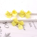 Three bright yellow satin ribbon bow hair clips displayed on a white textured background - Gold Yellow