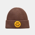 Détail d'un bonnet en tricot marron avec un patch sourire jaune sur le bord replié - Marron