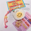 Gros plan d'une mini pochette en tricot blanc avec un smiley jaune et dragonne perlée - A05 Visage Souriant Blanc