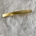 Detailopname van de lange gouden metalen haarklem met een geborstelde textuur - KC Goud