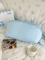 Dettaglio di un beauty case azzurro con cerniera su uno sfondo di tessuto bianco con conigli - Blu