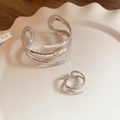 Primo piano del bracciale a spirale in argento lucido e set di anelli coordinati in un piatto - Set Bracciale e Anello Argento (2 Pezzi)