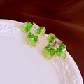 Macro view of emerald green crystal floral earrings on white ceramic with velvet back - Silver Needle Green Crystal Flower Stud Earrings