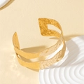 Detailed macro view of gold-plated titanium steel bracelet with hammered texture and hollow ends - 1080-Double Layer Hammered Rectangle Hollow Cuff