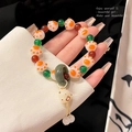 Elegant beaded bracelet featuring orange cat paw beads, red accents, and green charms - White/Cat Claw Shape
