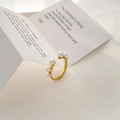 Detailopname van een verstelbare gouden parelring met parels op een witte ondergrond - US 6 / Parel Open