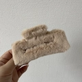 Detail of a large rectangular khaki faux fur hair claw clip held in hand for hair styling - Apricot