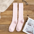 Chaussettes hautes en polaire corail rose en peluche douce sur une surface en bois - Rose Clair