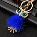 Macro view of crystal owl keychain with blue faux fur pompom and green gemstone eyes - Plush Owl Royal Blue