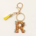 Letter R acrylic keychain with honeycomb bee pattern and yellow tassel detail - Letter R