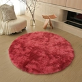 Soft plush round rug in vibrant red faux fur, displayed on a wooden floor in a living room - Tie-dye Wine Red
