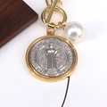 Detalle de un colgante de moneda vintage con grabado de la Virgen y una perla blanca - Plata Grande