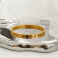 Detailed view of golden rippled texture on a stylish titanium steel open bangle - Plaid Pattern