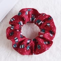 Red plush Christmas scrunchie with festive patterns on white faux fur background - Red Cartoon Santa Hat